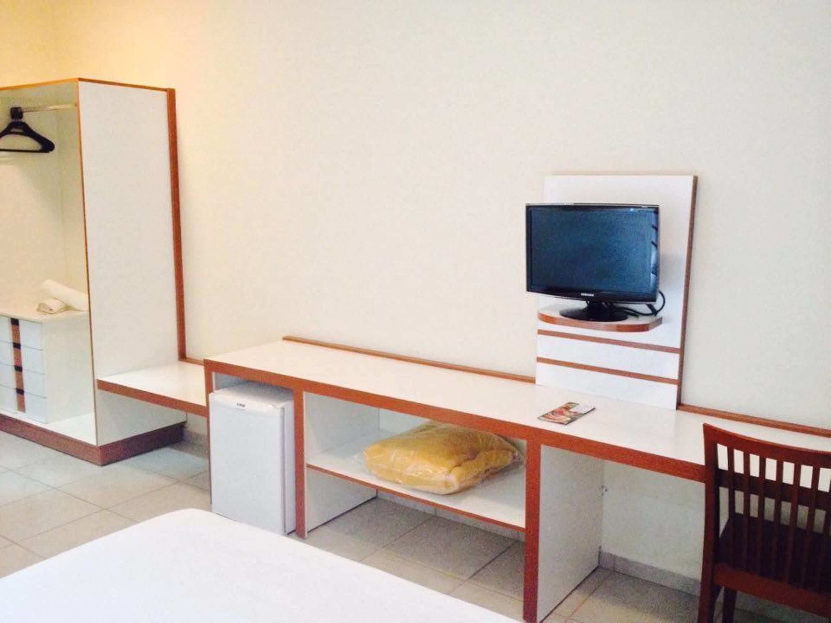 Una habitación de hotel con cama, escritorio con computadora, televisión y silla.