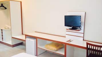 Una habitación de hotel con cama, escritorio con computadora, televisión y silla.