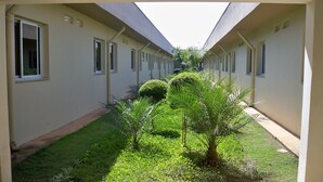 A corridor with a skylight, lined with windows, and a small garden area with grass and plants. - Habitat Hotel Pirassununga (Pirassununga)