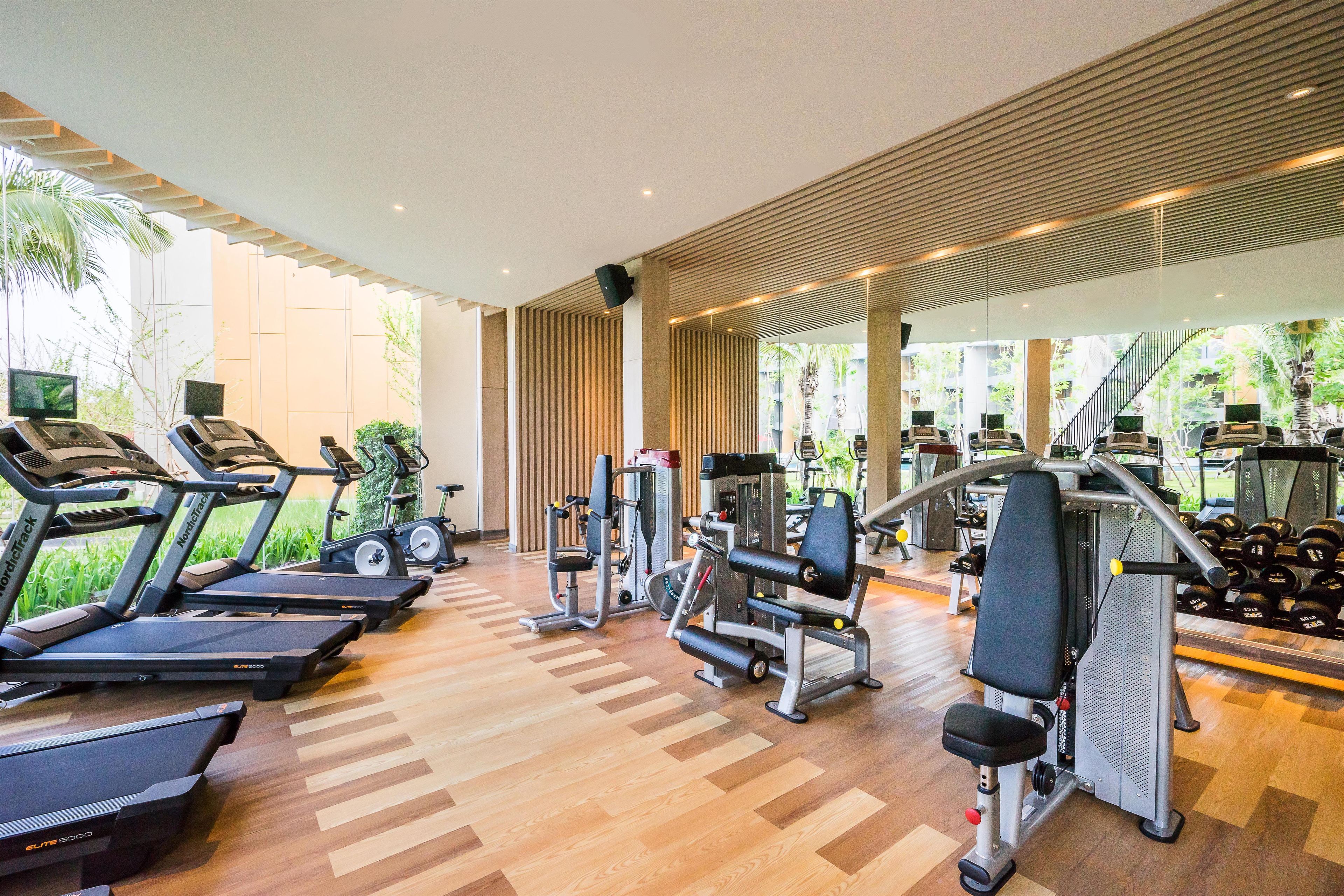 A gym with treadmills, weight machines, and dumbbells.