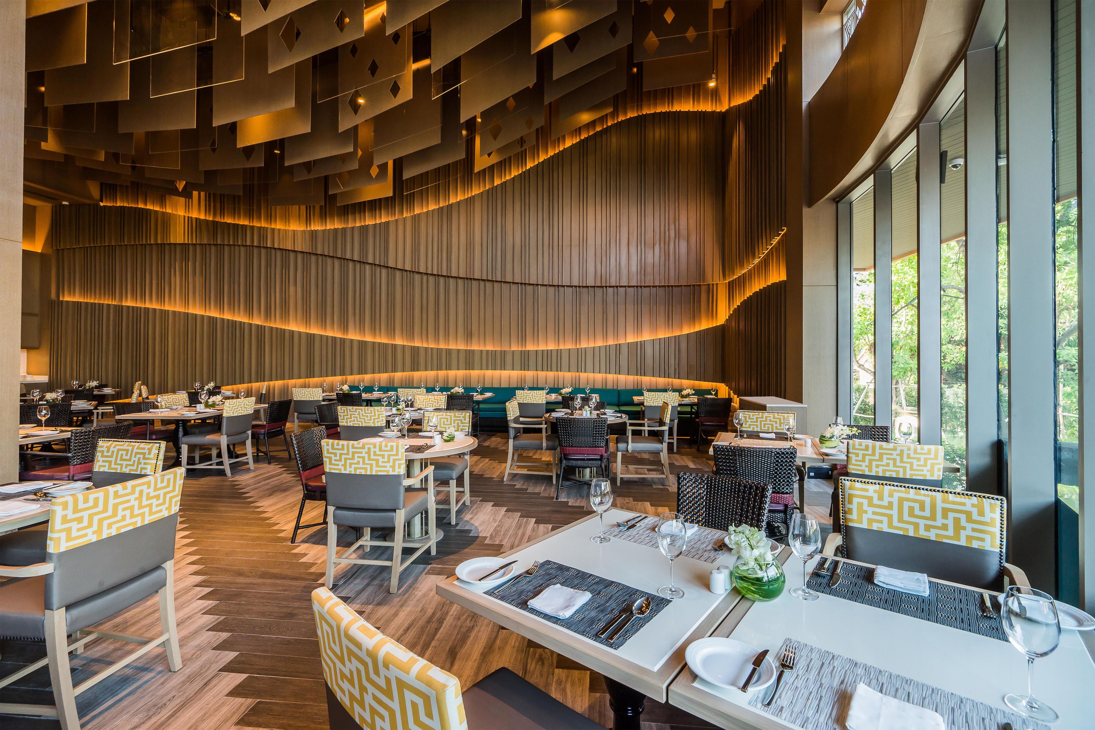A modern restaurant with a variety of seating options, including booths and tables, and a large window providing a view of the outdoors.