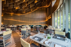 A modern restaurant with a variety of seating options, including booths and tables, and a large window providing a view of the outdoors.