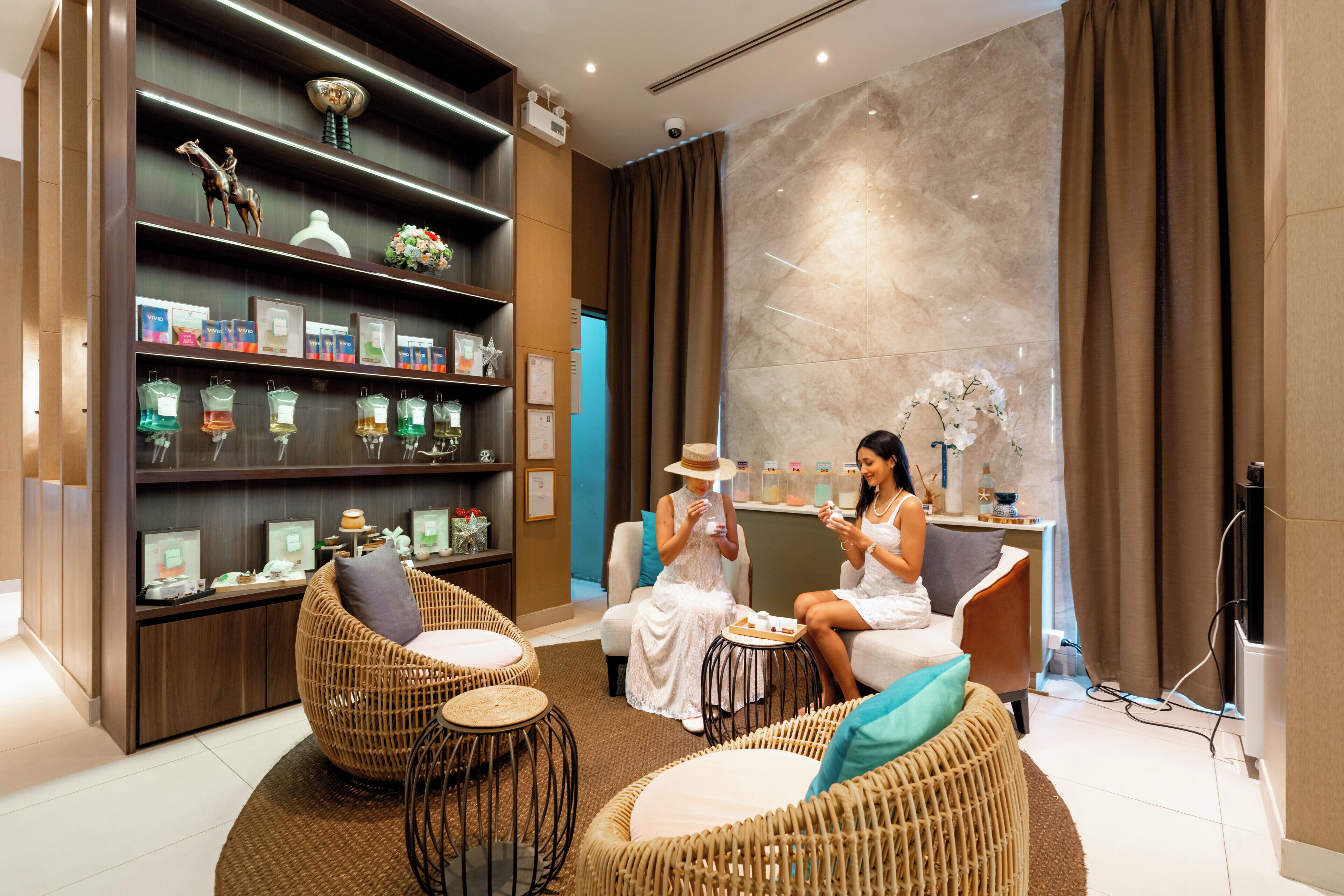 Un espace spa moderne avec des meubles en osier, un comptoir d’accueil et une étagère murale où sont exposés les produits.