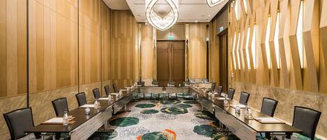 A conference room with a long table, chairs, and a patterned carpet.