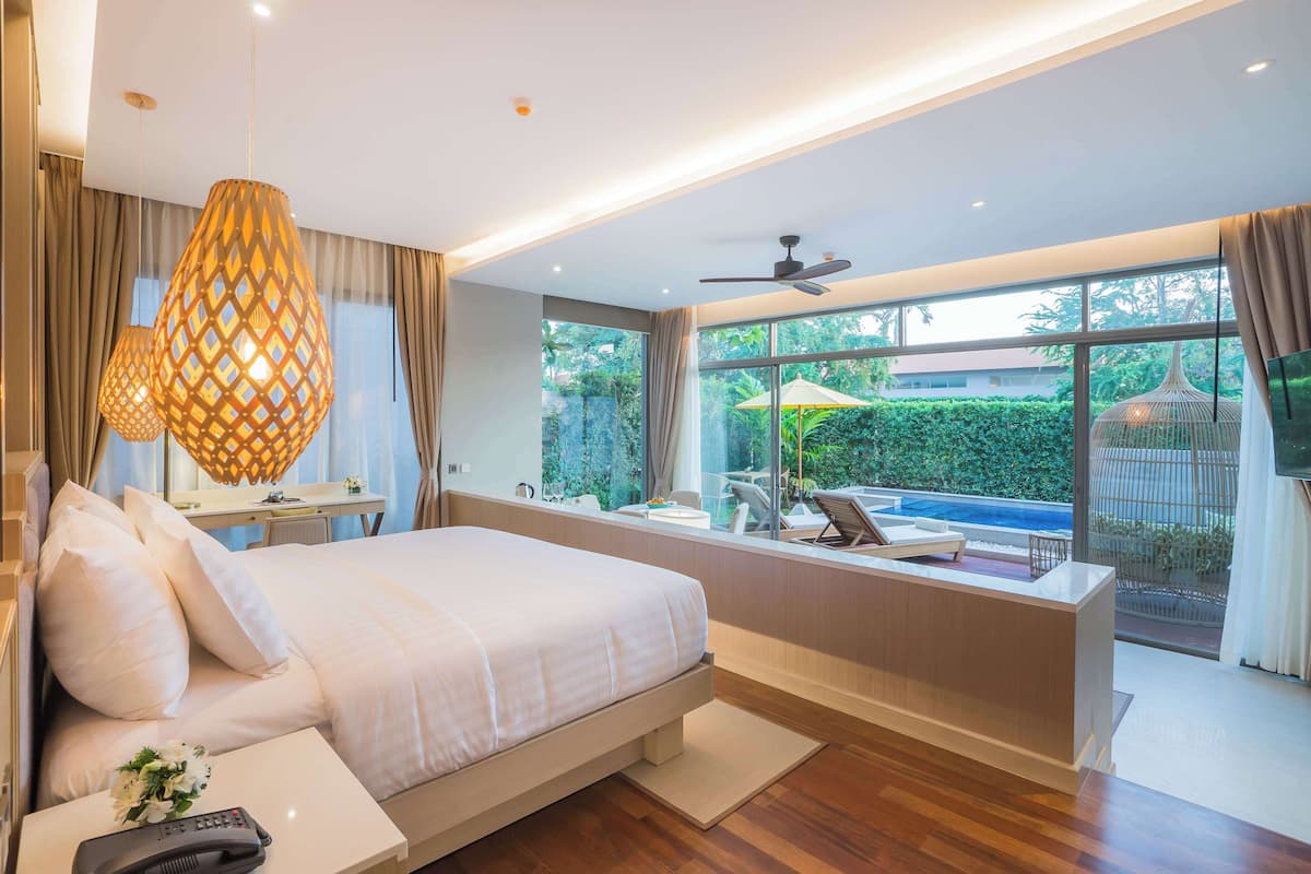 Een moderne slaapkamer met een groot bed, een bureau en uitzicht op een zwembad.