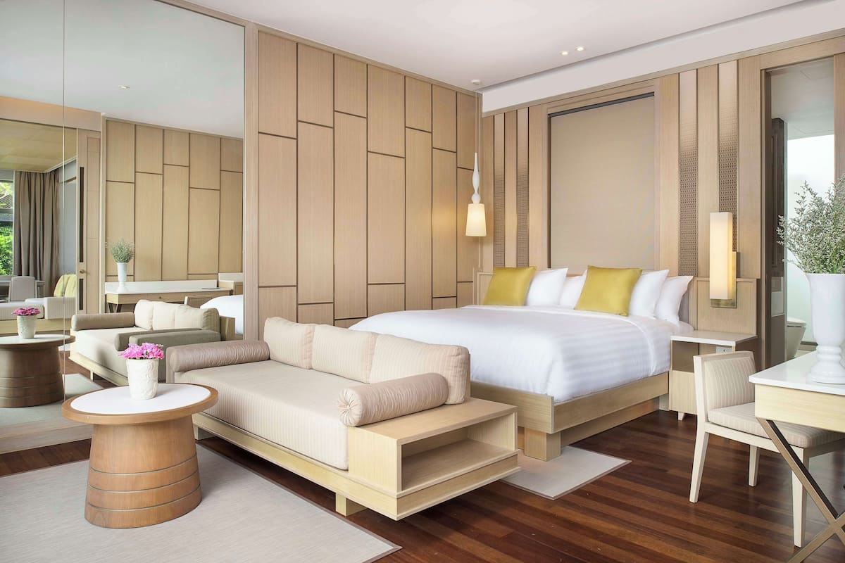 Een moderne hotelkamer met een groot bed, een slaapbank, een bureau en een spiegel.