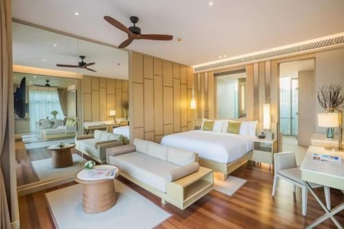 Een moderne hotelkamer met een bed, bank, bureau en plafondventilator.
