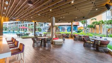 An outdoor seating area with wooden flooring, tables, and chairs.