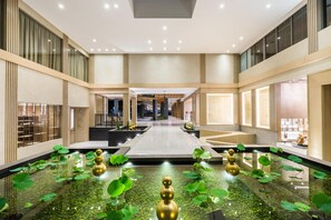 A spacious atrium with a central water feature, surrounded by seating areas and a view of the hotel's interior.