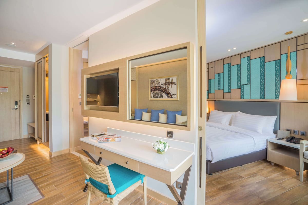 Een hotelkamer met een bed, een bureau, een stoel, een spiegel en een nachtkastje.