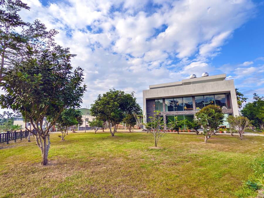 A modern building with a flat roof, large windows, and a grassy courtyard with trees.