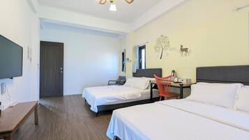 Une chambre d’hôtel avec deux lits, un bureau, une chaise, une télévision et un ventilateur de plafond.