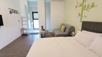Una habitación de hotel con cama, sofá, escritorio y televisión montada en la pared.