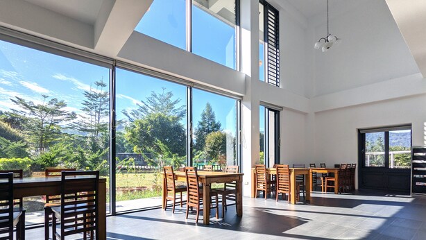 Un comedor amplio con ventanas grandes, techo alto y vistas a zonas verdes y montañas.