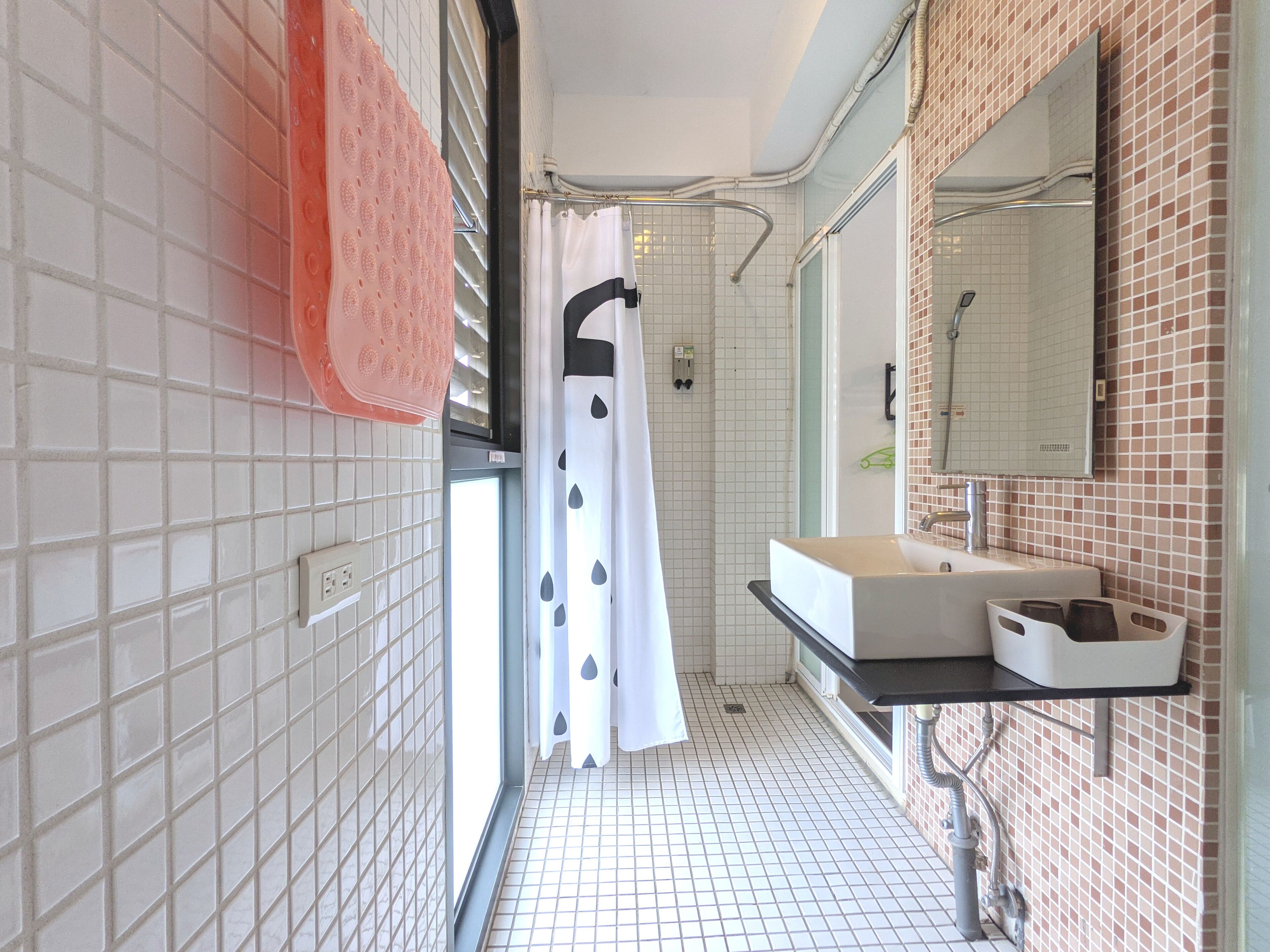 A narrow bathroom with a white sink, a mirror, and a shower curtain.