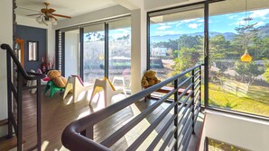 Un balcón amplio con vistas a un paisaje exuberante, un ventilador de techo y una zona de estar con sillas y una mesa.