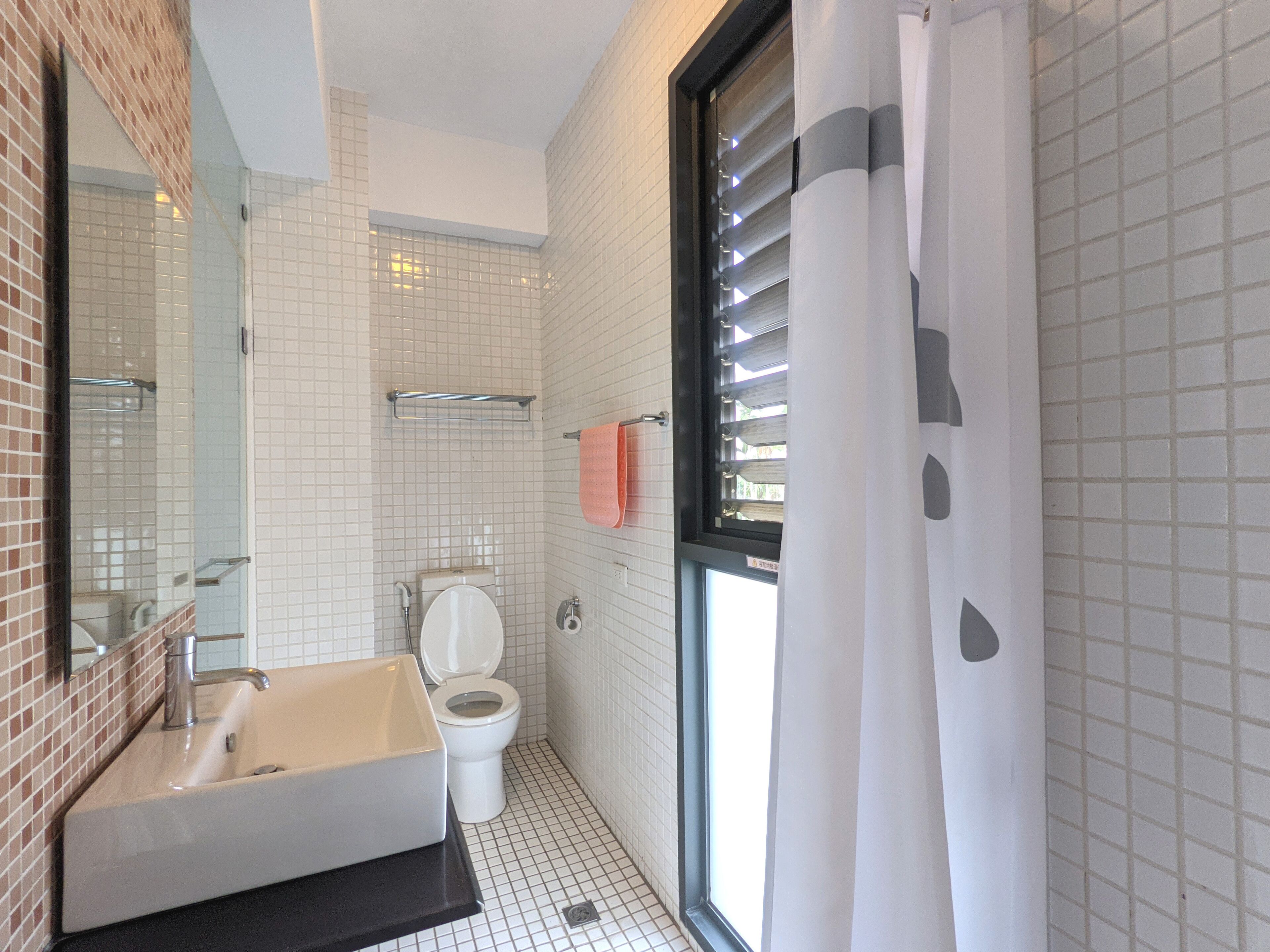 Ein Badezimmer mit Waschbecken, Toilette und einem Fenster mit Jalousien.