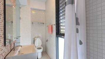 Ein Badezimmer mit Waschbecken, Toilette und einem Fenster mit Jalousien.