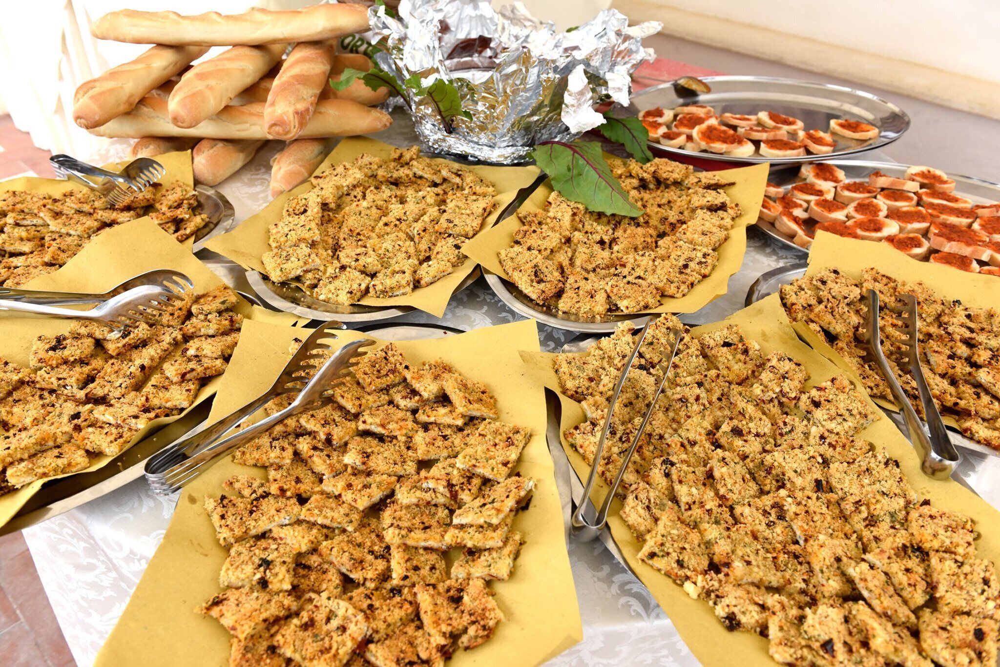 Un tavolo con diversi cibi, tra cui pane e snack sbriciolati, apparecchiato per servire.