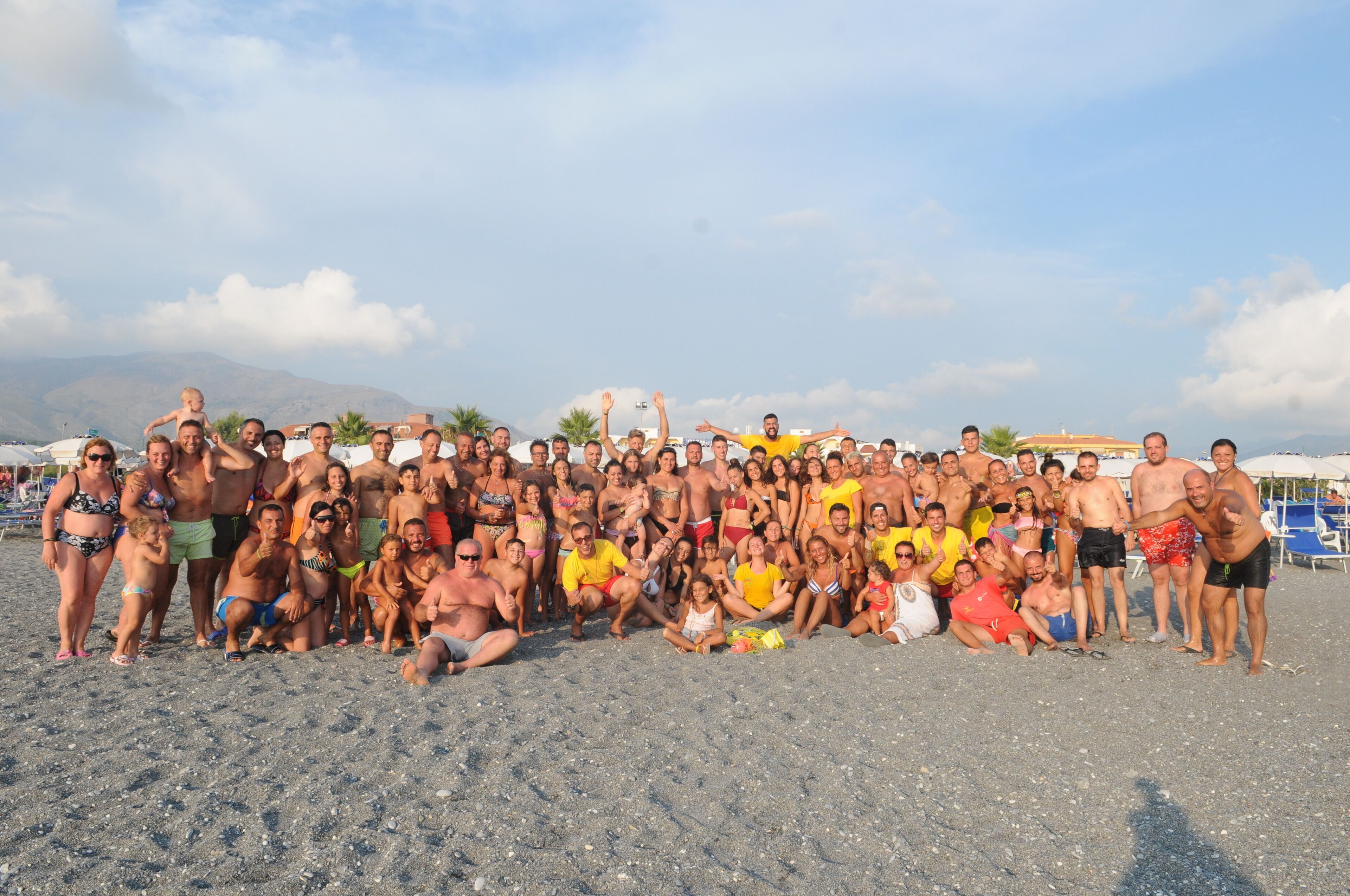 Un grupo de personas en la playa, con sombrillas y sillas de fondo.
