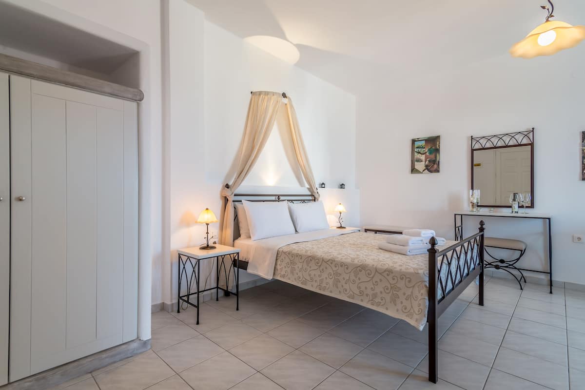 A bedroom with a bed, bedside tables, a nightstand, a desk, and a mirror.