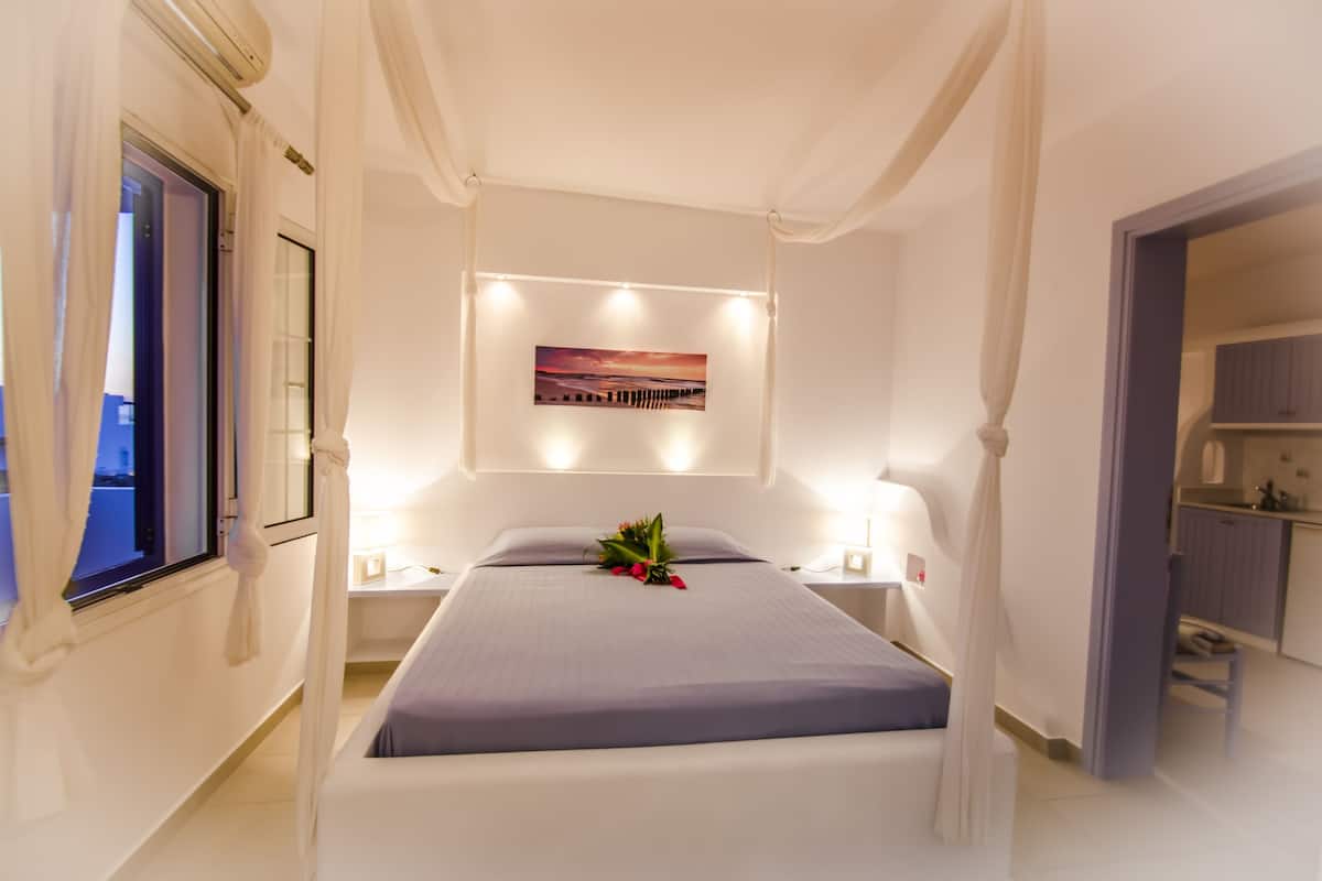 A neatly arranged bedroom with a bed, bedside lamps, a wall-mounted picture, and a small table with a flower arrangement.