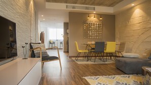 Una sala de estar moderna con piso de madera, un sofá, una mesa de comedor con sillas y un adorno en la pared.
