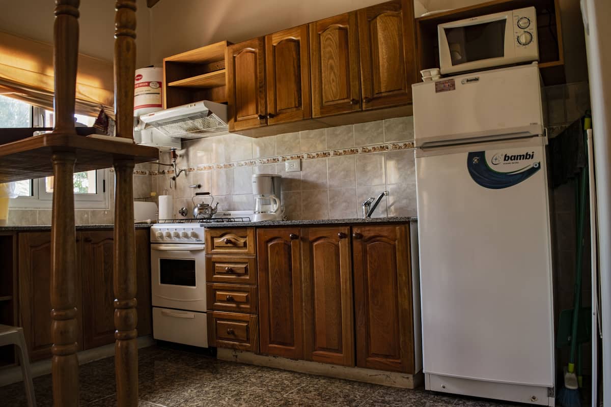 A kitchen with wooden cabinets, a stove, a microwave, and a refrigerator.