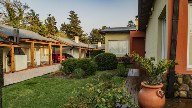 Ein Wohnhaus mit überdachter Terrasse, einem roten Auto vor der Einfahrt und einem gepflegten Rasen.