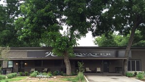 A building with a sign reading "NEWATER" and a covered outdoor seating area with chairs. - Whitewater Condos (Canyon Lake)
