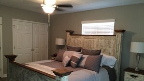 A bedroom with a bed, a ceiling fan, a window, and a nightstand. - Whitewater Condos (Canyon Lake)