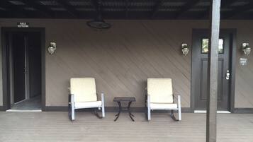 A covered outdoor seating area with two chairs and a small table, a sign for public restrooms, and a door labeled "UNIT C".