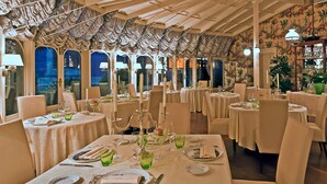 A restaurant with round tables set for dining, featuring white tablecloths and candle centerpieces. - Resort Dei Limoni (Lucca)