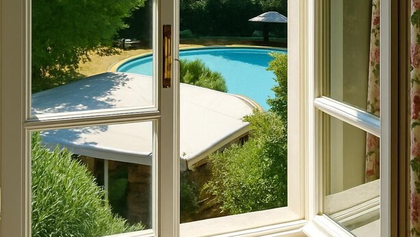 A view through a window with a pool and greenery visible outside. - Resort Dei Limoni (Lucca)