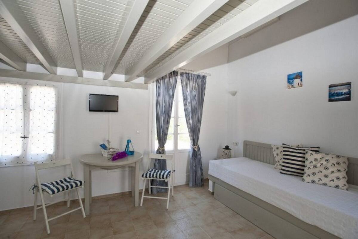 A room with a bed, a desk, a chair, a TV, and curtains.