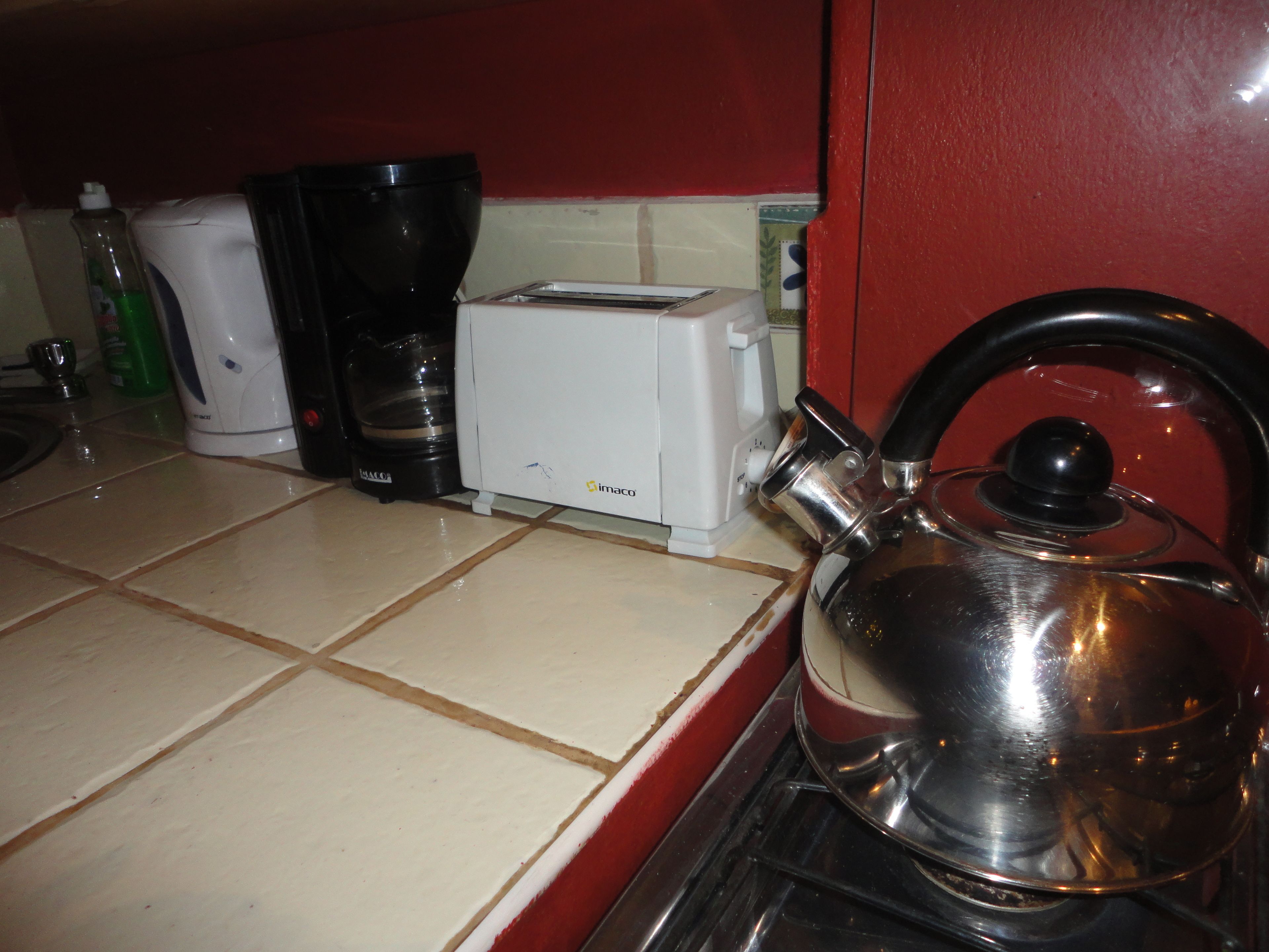 Una cocina con cafetera, tostadora, hervidor y una botella de detergente.