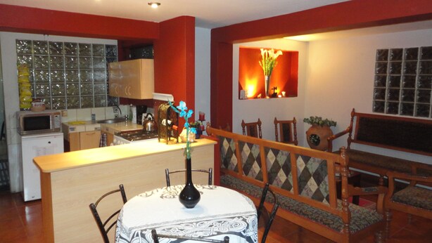 Un comedor con una mesa y sillas, una cocina al fondo y un ventanal decorado con flores.