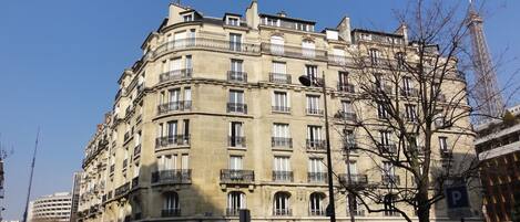Un immeuble à plusieurs étages, de style architectural classique, doté de balcons et d’une entrée centrale.