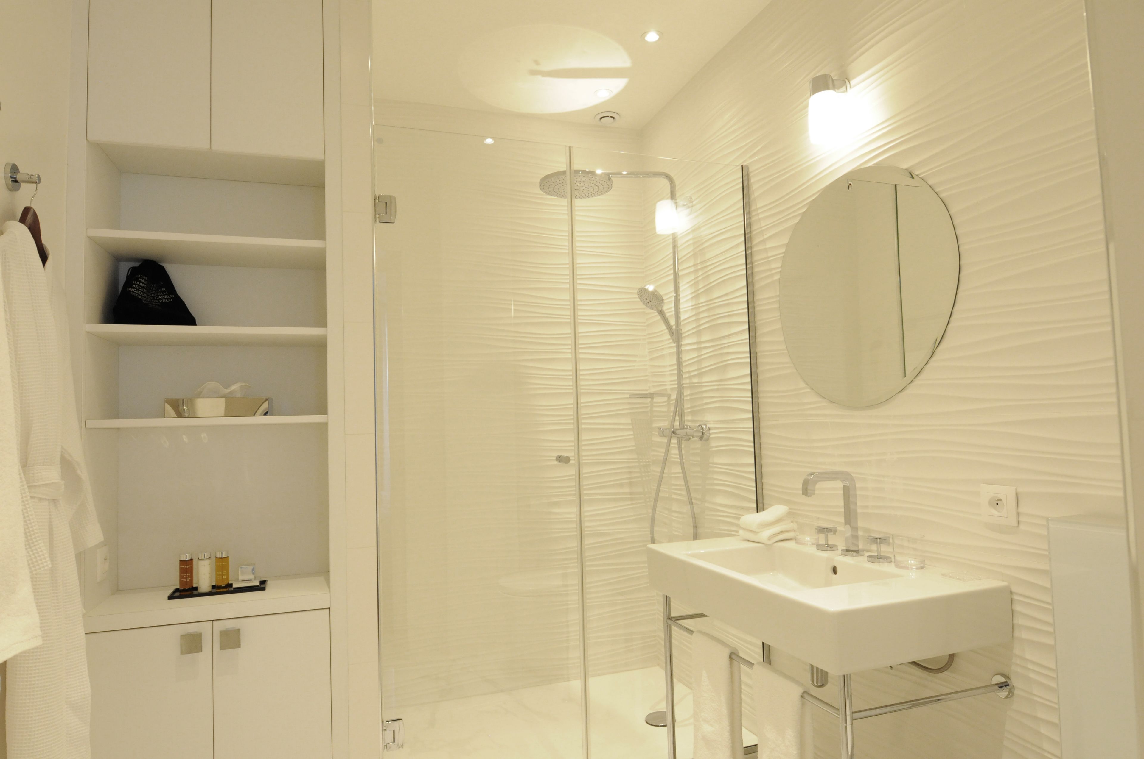Une salle de bain moderne avec une douche à parois de verre, un lavabo blanc et un miroir au mur.