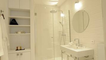 Une salle de bain moderne avec une douche à parois de verre, un lavabo blanc et un miroir au mur.