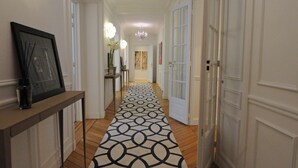 A hallway with a patterned carpet, white doors, and a chandelier. - Relais 12bis B&B (Paris)