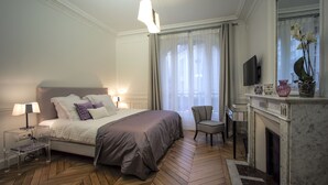 A hotel room with a large bed, a chair, a fireplace, and a television. - Relais 12bis B&B (Paris)