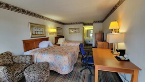 Una habitación de hotel con dos camas, un escritorio, una silla y una mesita.
