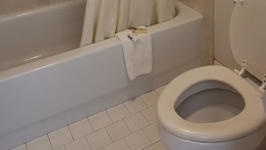 Un baño con bañera, inodoro y cortina de ducha.