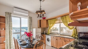 A modern kitchen with a dining area, large windows, and a view of the city. - Bay View Apartment by Getaways Malta (St. Paul's Bay)
