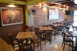 Interior de un restaurante con paredes de ladrillo, mesas y sillas de madera.