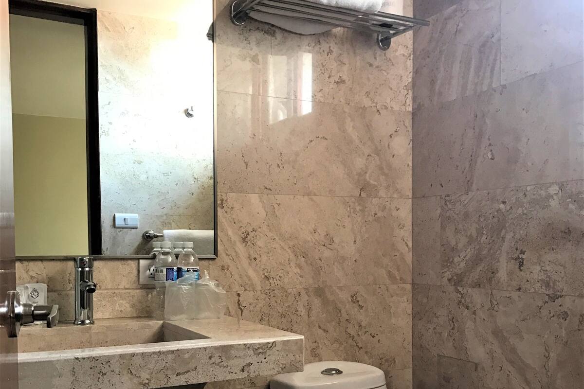 A bathroom with a marble sink, a toilet, and a towel rack.