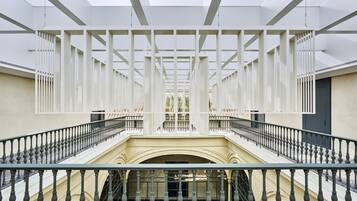 A spacious interior with a central staircase flanked by white columns and railings.