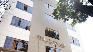 The entrance to El Prado Hotel with a gated entrance, visible windows, and a sign indicating payment options. - Hotel El Farolito (Lima)