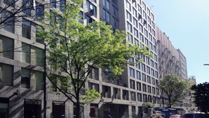 Un edificio moderno con fachada de vidrio y un árbol en primer plano.